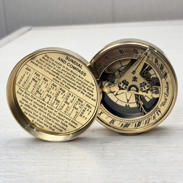 Open brass sundial compass showing the sundial face on one side and a perpetual calendar inside the lid.