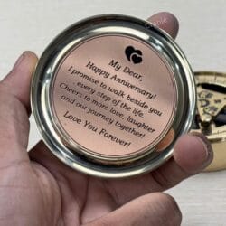 Close-up of the "Happy Anniversary" engraved message inside the lid of the brass compass, held in hand.
