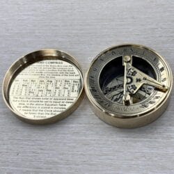 Fully open brass pocket compass displaying the detailed sundial on one side and a perpetual calendar on the other.