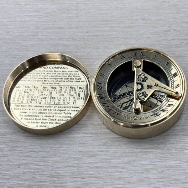 Fully open brass pocket compass displaying the detailed sundial on one side and a perpetual calendar on the other.