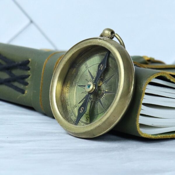 The vintage brass compass resting on a leather-bound journal, symbolizing travel and adventure.