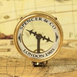 An angled view of the Spencer & Co. brass map reader compass, showing the magnifying glass lens and vintage dial.