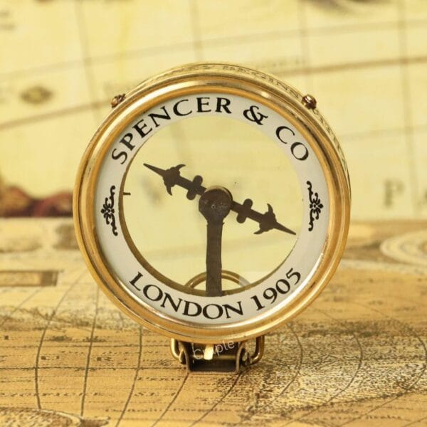 An angled view of the Spencer & Co. brass map reader compass, showing the magnifying glass lens and vintage dial.