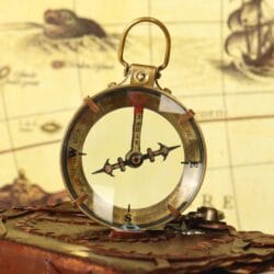 Atmospheric shot of the brass magnifying compass on a book, showing the compass needle and cardinal points.
