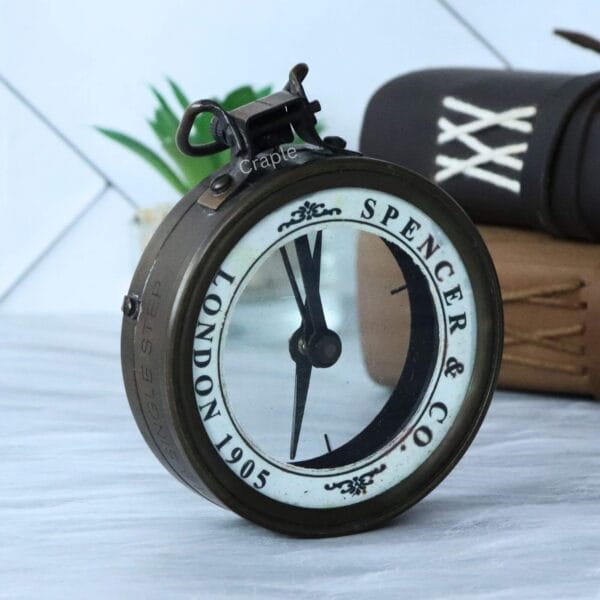 Angled view of the antique brass map reader compass, showing the Spencer & Co. branding on the white chapter ring.
