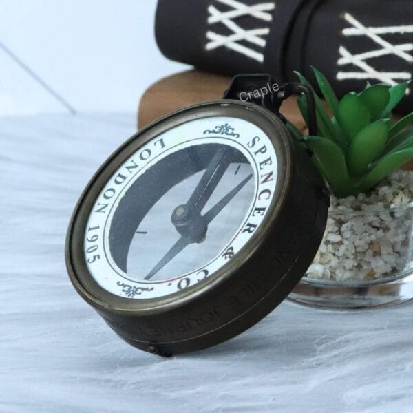 The antique brass map reader compass tilted back to show the reflective magnifying glass lens.