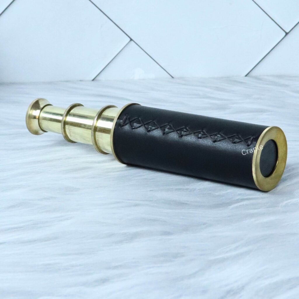 Fully extended brass pocket telescope with a hand-stitched black leather wrap, showcasing its full length and polished finish.