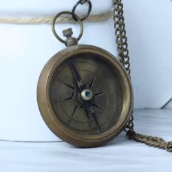 Vintage-style open-face pocket compass in antique brass, with its matching chain partially visible.