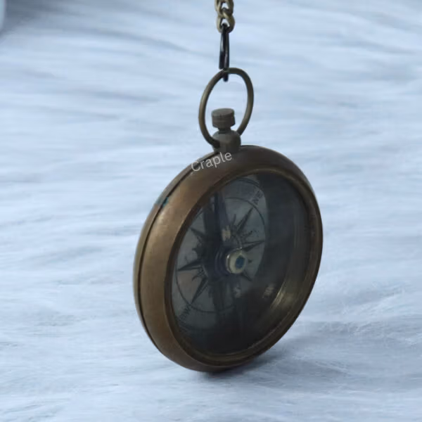 Angled side profile of the antique brass pocket compass, highlighting its solid, rounded construction.