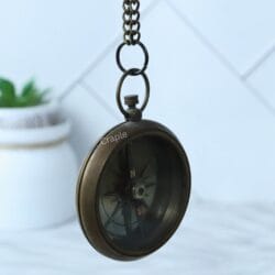 The hanging open-face brass compass tilted at an angle, showing the depth of the casing.