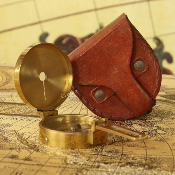 An open brass Brunton compass displayed next to its handcrafted brown leather carrying case.