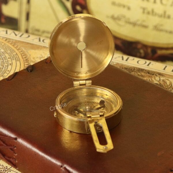 Polished brass pocket compass with the lid open, revealing the reflective interior mirror and dial.
