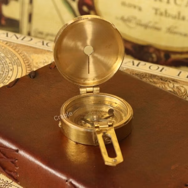 Polished brass pocket compass with the lid open, revealing the reflective interior mirror and dial.