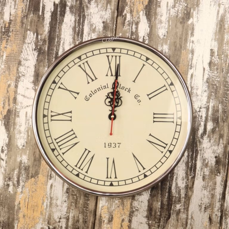 Vintage-style wall clock with a polished silver steel frame, a cream face, and black Roman numerals.