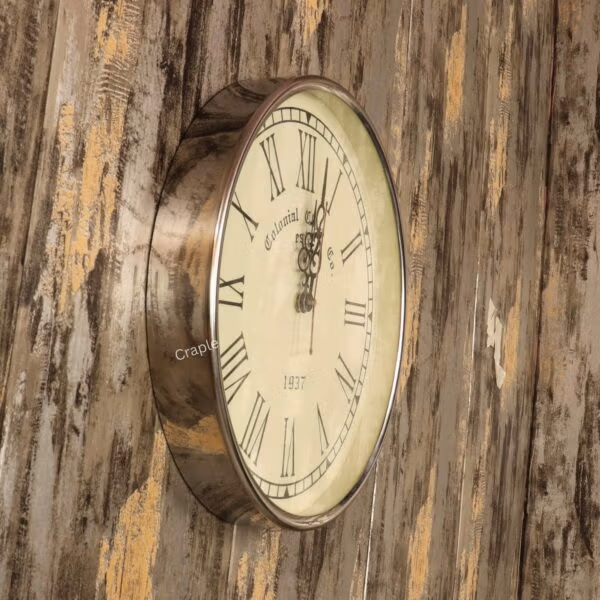 Angled view of the round silver steel wall clock mounted on a rustic wooden wall.