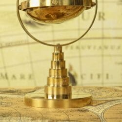 Detailed view of the polished, tiered solid brass stand for the tabletop gimbal compass.