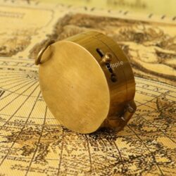 The back of the closed, shiny brass pocket compass, showcasing its smooth, polished finish and hinge.