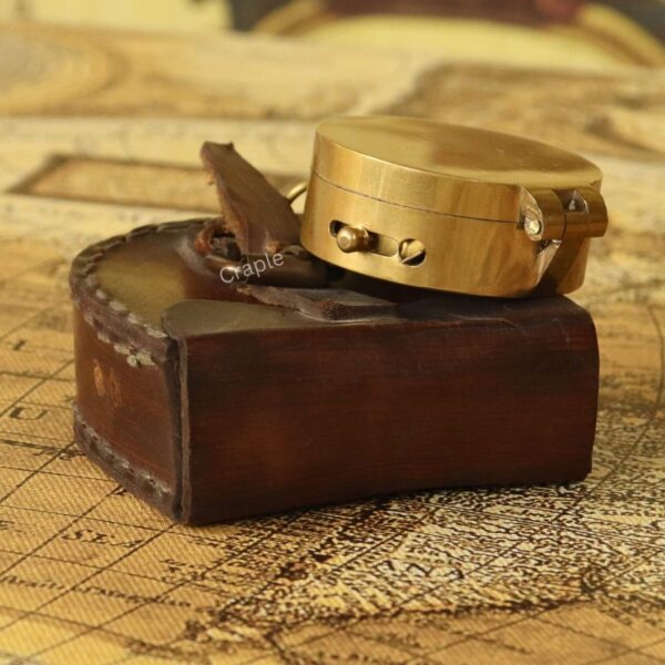 Shiny Brass Pocket Compass with Mirror-8 The vintage brass compass being placed into its custom-fit brown leather pouch with a strap closure.