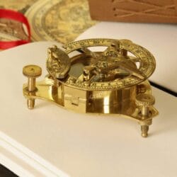 Detailed close-up of a polished brass West London sundial compass, showing the intricate gnomon and adjustment screws.