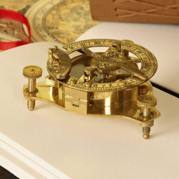 Detailed close-up of a polished brass West London sundial compass, showing the intricate gnomon and adjustment screws.