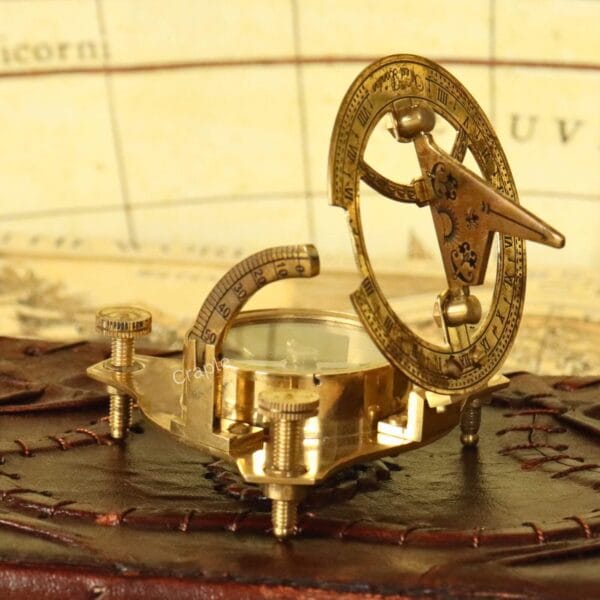 Vintage-style shiny brass sundial compass with its gnomon raised, displayed on a leather-bound book.