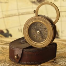Antique brass sliding desk compass with its flip-up magnifier open, emerging from a stitched leather case.