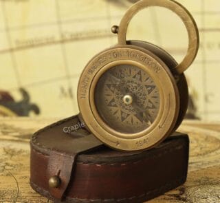 Antique brass sliding desk compass with its flip-up magnifier open, emerging from a stitched leather case.