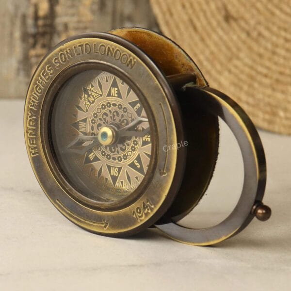 Side-angled view of the Henry Hughes antique-style brass compass with the magnifying glass extended.