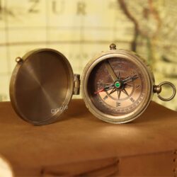 An open antique brass pocket compass with a detailed dial, showing the cardinal points and needle.