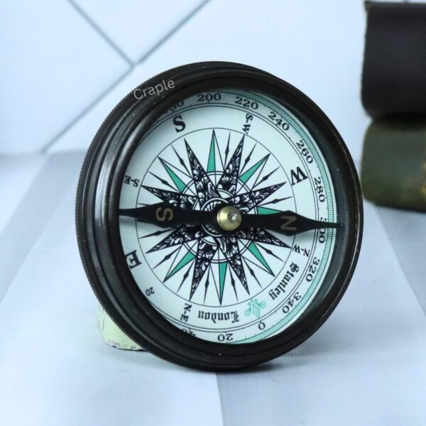 Angled view of the open Stanley London compass, focusing on the detailed compass rose and directional needle.