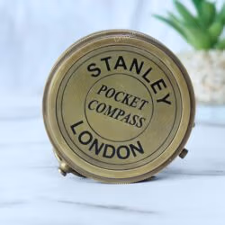 Front view of the Stanley London pocket compass with its engraved antique brass lid closed.