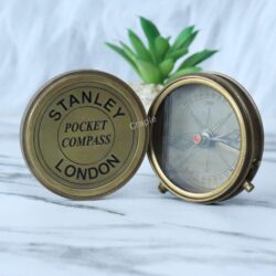 Vintage Stanley London pocket compass displayed with its engraved lid propped next to the open compass dial.