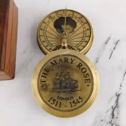Open brass sundial compass with its engraved "The Mary Rose" lid resting beside it.