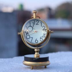Close-up of the tilting brass tabletop clock outdoors, focusing on the details of the clock face and frame.