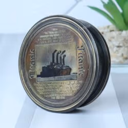 Antique black brass pocket compass with an embossed Titanic lid, shown at an angle to display its depth and detail.