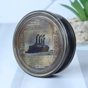 Antique black brass pocket compass with an embossed Titanic lid, shown at an angle to display its depth and detail.