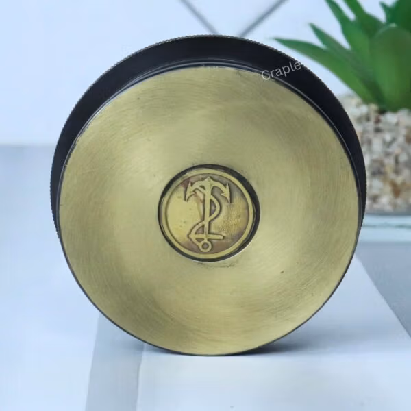 The back of the round brass compass showing the smooth, golden brass finish on the reverse side.