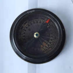 Extreme close-up of the antique compass dial, showing the needle, intricate markings, and cardinal points (N, S, E, W).