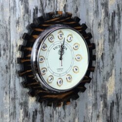 Angled view of the decorative gear-shaped wooden clock, showing the depth of the cog teeth and the rustic finish.