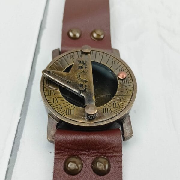 Close-up of the antique brass sundial compass face, showing the triangular gnomon and the compass needle below.