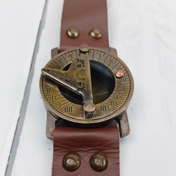 Close-up of the antique brass sundial compass face, showing the triangular gnomon and the compass needle below.