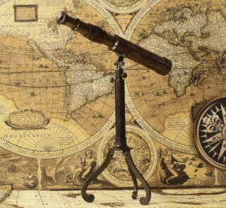 Vintage W. Ottway brass telescope with a black antique finish, mounted on a decorative foldable tripod stand.