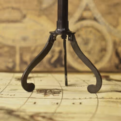 Close-up of the elegant, curved legs of the black antique finish brass tripod stand for the decorative telescope.
