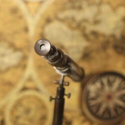 View of the eyepiece of the antique-style brass tabletop telescope, aimed over a vintage map.