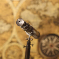 View of the eyepiece of the antique-style brass tabletop telescope, aimed over a vintage map.