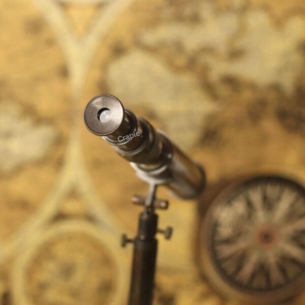 View of the eyepiece of the antique-style brass tabletop telescope, aimed over a vintage map.