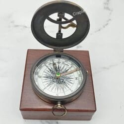 Open antique brass sundial compass with a black finish, displayed inside its polished wooden storage box.