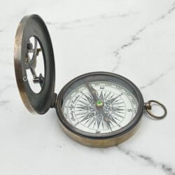 Vintage West London pocket compass with its lid open, showing the detailed "compass rose" dial and needle.
