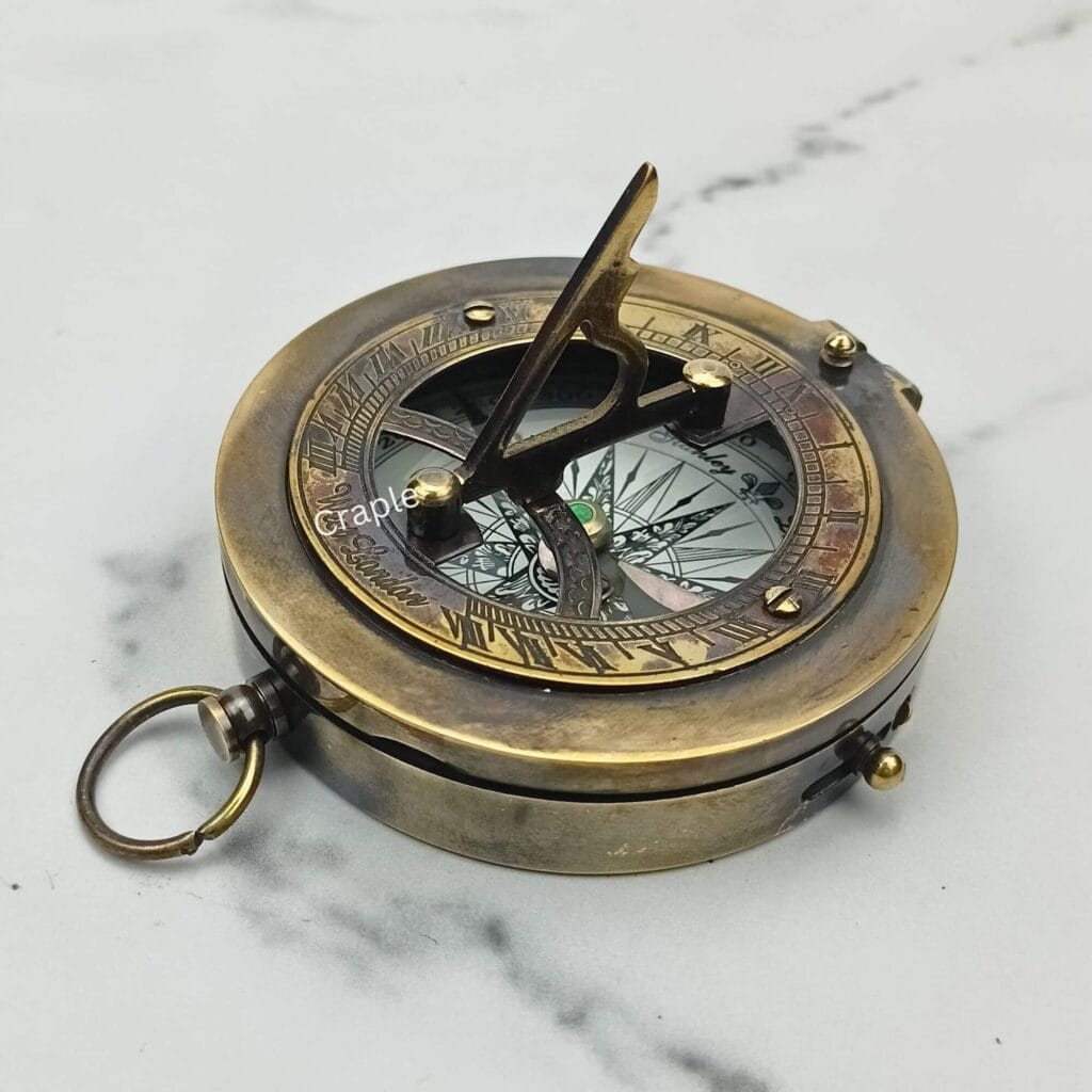 Antique brass pocket sundial compass with a black finish, its triangular gnomon raised for telling time.