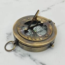 Antique brass pocket sundial compass with a black finish, its triangular gnomon raised for telling time.